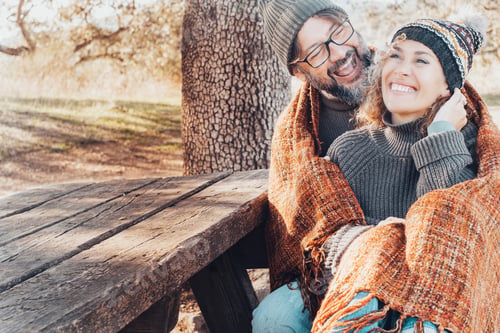 Preview: Adult couple have fun together with love and laughing sitting together on a bench in autumn season