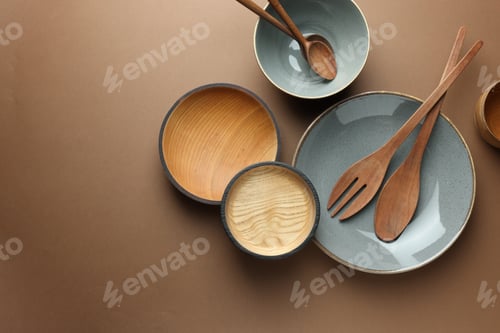 Preview: Stylish empty dishware and wooden cutlery on brown background, flat lay. Space for text