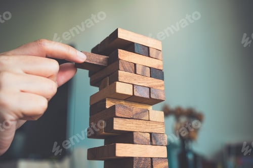 Preview: Closeup image of a hand holding and playing Tumble tower wooden block game
