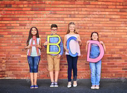 Preview: Portrait of a group of young children holding letters from the alphabet against a brick wall