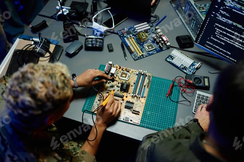 Preview: Young female officer in military uniform repairing motherboard by desk