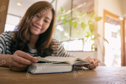 Preview: Closeup image of a beautiful asian woman holding and reading a book