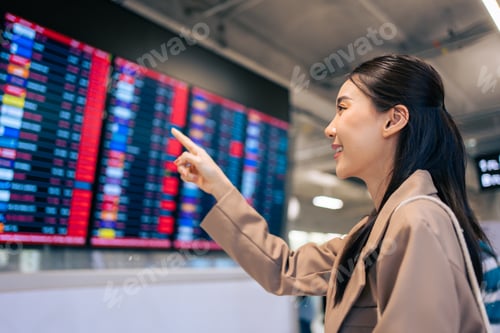 Preview: Asian young woman passenger checking depature boarding pass in airport.