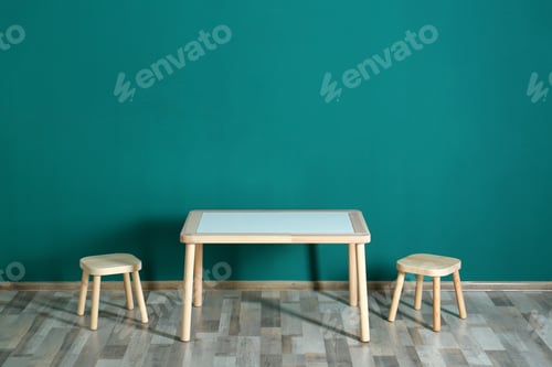Preview: Table with chairs near turquoise wall in baby room interior. Space for text
