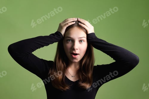 Preview: Teen Girl Expresses Surprise in Studio With Green Background and Emotional Pose