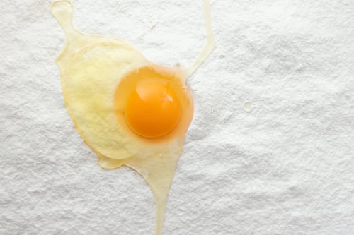 Preview: Raw egg on flour white background, top view. Cooking and baking concept
