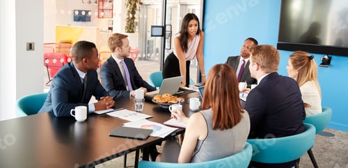 Preview: Female manager stands addressing colleagues in meeting room