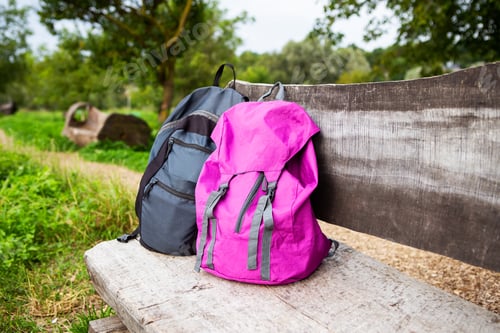 Preview: Two bright backpacks stand on a wooden bench in the street. Outdoor recreation. Trekking in the