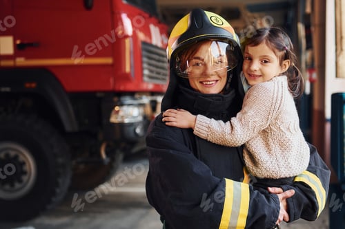 Preview: Happy little girl is with female firefighter in protective uniform