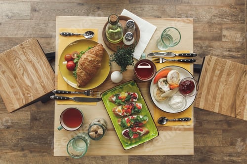 Preview: top view of tasty healthy breakfast with cheesecakes and sandwiches on table