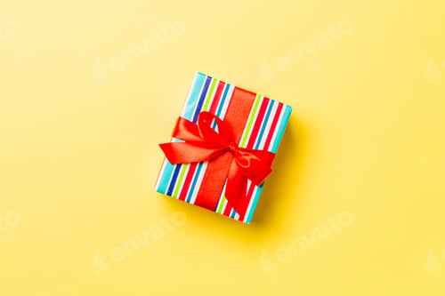 Preview: Top view Christmas present box with red bow on yellow background with copy space