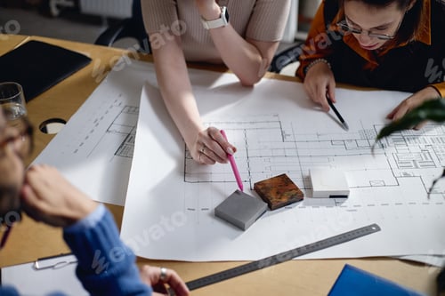 Preview: Young Adult Women Collaborating on Architectural Blueprint in Office Setting
