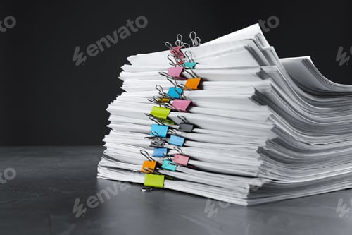 Preview: Stack of documents with binder clips on grey stone table against black background