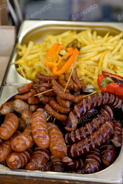 Preview: Grilled sausage with the addition of herbs and vegetables on the grill plate