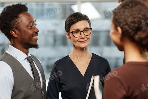 Preview: Group of successful business people standing in circle in office and smiling