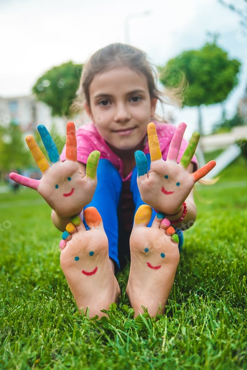 Preview: Feet of a child on the grass with a painted smile. Selection focus.