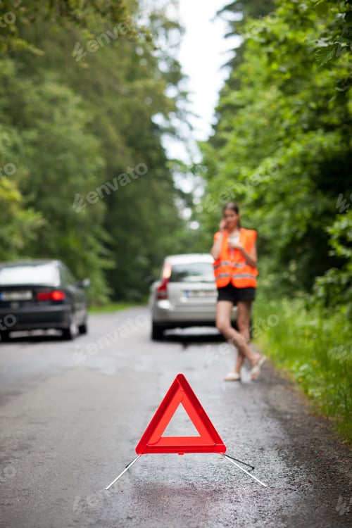 Preview: Young female driver wearing a high visibility vest, calling the