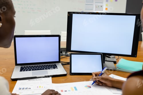 Preview: Cropped image of african american coworkers analyzing reports by laptop and computer on desk