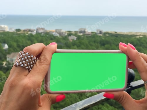 Preview: Gen Z holds mockup friendly mobile device with solid green screen for copy space text overlay