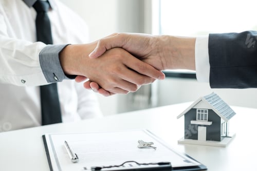 Preview: Businessmen and brokers' real estate agents shake hands after completing negotiations to buy houses