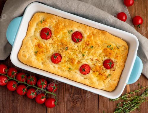 Preview: appetizing golden focaccia with tomatoes and spices, on dark wooden rustic table