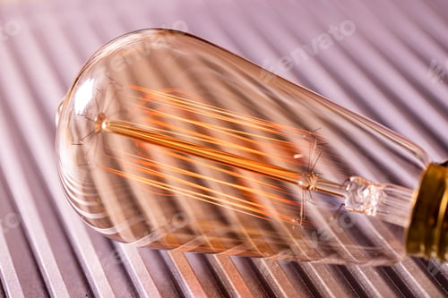 Preview: An incandescent lamp shines lying on a metal surface in a workshop in the evening light