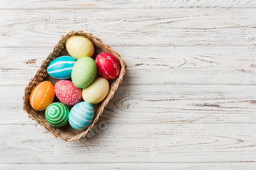 Preview: Multi colors Easter eggs in the woven basket on colored background