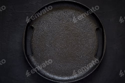 Preview: Empty rustic cast iron plate On a black background. Top view wit