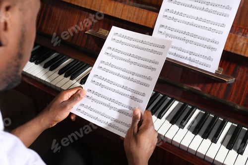 Preview: African-American man with note sheets at piano, closeup. Talented musician