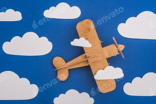 Preview: top view of wooden plane in blue sky with paper cut white clouds