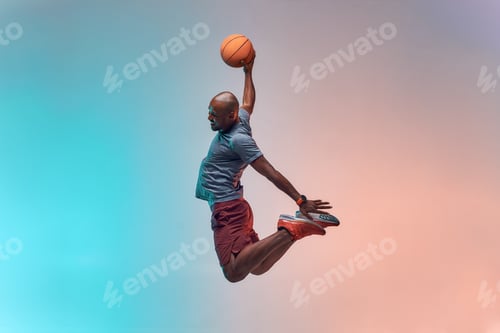Preview: Slam dunk. Full length of young african backetball player jumping against colorful background