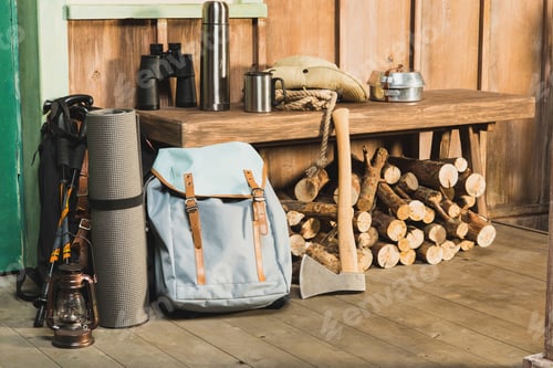 Preview: different trekking equipment on bench near wooden house waiting for traveler
