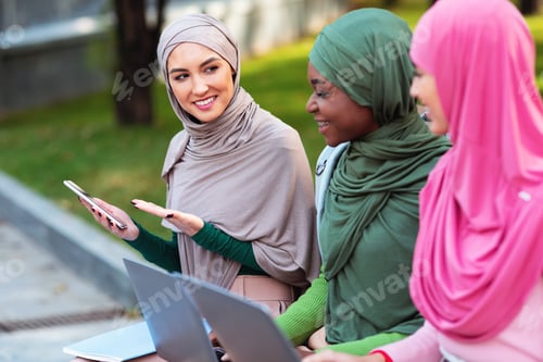 Preview: Muslim Female Student Recommending Mobile App To Friends Learning Outside