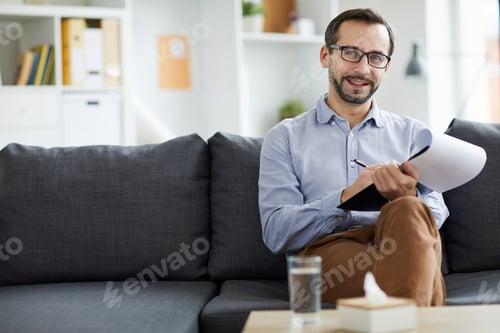 Man Sitting on Couch Holding Clipboard and Pen