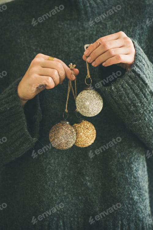 Preview: Woman in grey sweater holding golden and silver balls