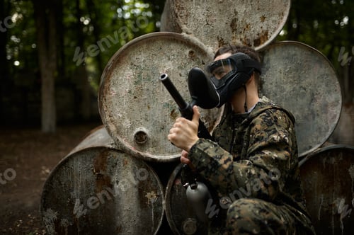 Preview: Female warrior in camouflage holds paintball gun