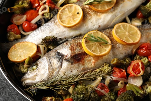 Preview: Baked fish with vegetables, rosemary and lemon on black textured table, top view