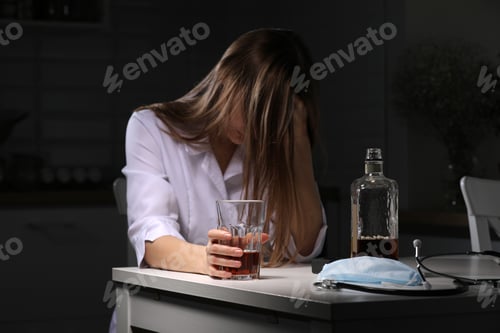 Preview: woman drinking alcohol in the kitchen. Young woman suffering from strong headache or migraine sitti