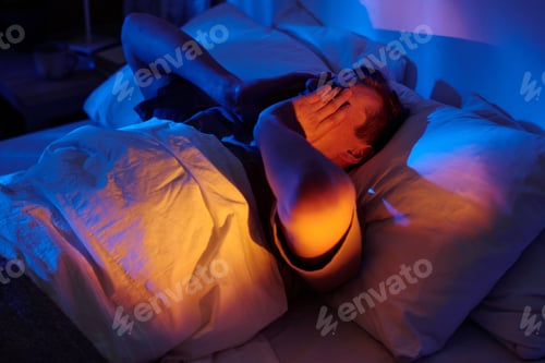 Preview: Man Lying in Bed Struggling with Insomnia at Night