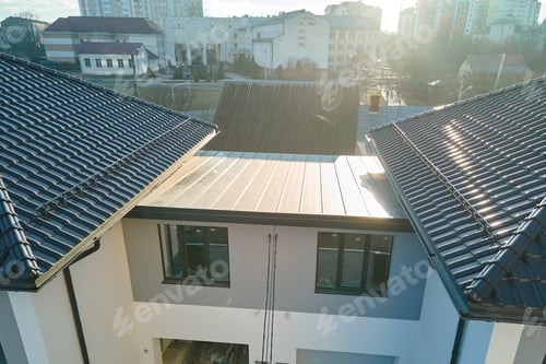 Preview: Closeup of house roof top covered with ceramic shingles with gutter pipes for rain water.