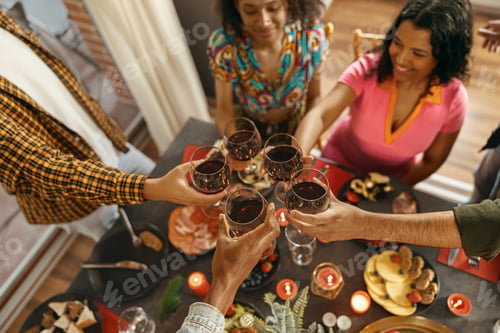 Preview: Close up of smiling friends drinking wine and enjoying time together at holiday dinner party