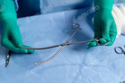 Preview: close-up in the operating room the hands of a doctor in green gloves hold surgical instruments