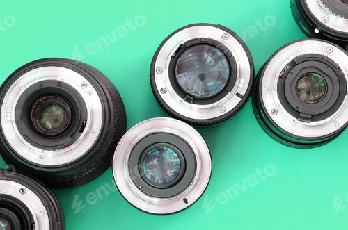 Preview: Several photographic lenses lie on a bright turquoise background. Copy space
