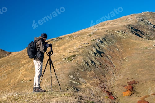 Preview: A photographer takes a photo of a beautiful mountain landscape with colorful trees