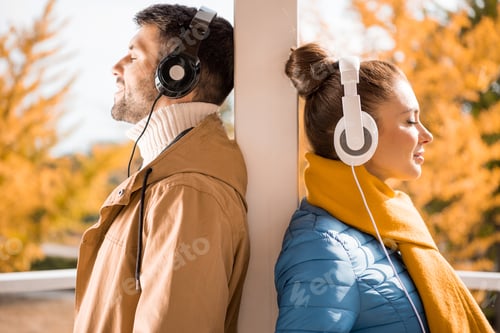 Preview: Side view portrait of handsome young man and beautiful woman standing in headphones at sunny autumn
