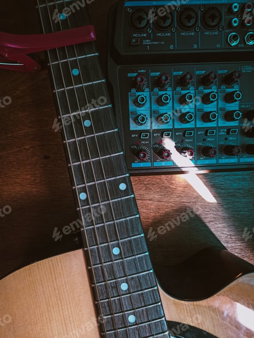Preview: Overhead shot of a guitar with a sound mixer on a wooden surface