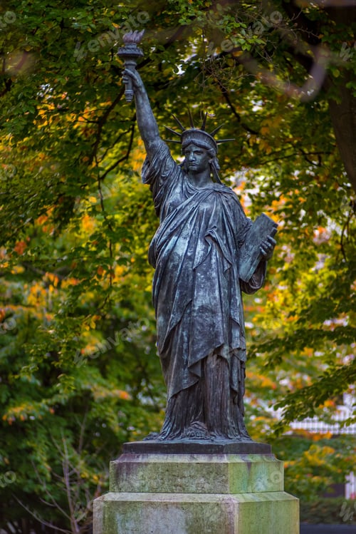 Preview: Vertical shot of the Statue of Liberty surrounded by greenery in Luxembourg Gardens, Paris