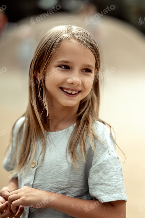 Preview: portrait of a beautiful 6-7-year-old girl with long blonde hair. A girl walks in the park
