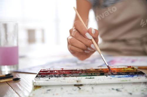 Preview: Person Painting with Watercolors Indoors on Wooden Table