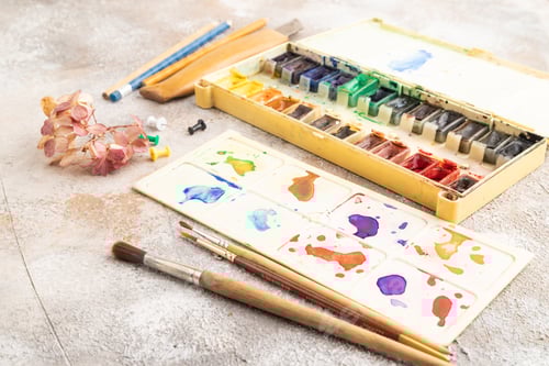 Preview: Drawing accessories set: brushes, pencils, watercolor on brown concrete. Side view